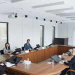 Grupo multicultural de profissionais reunido à volta de uma mesa numa sala de conferências moderna.