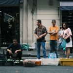 Feira de rua movimentada em São Paulo, com pessoas circulando entre bancas de produtos frescos.