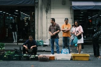 Feira de rua movimentada em São Paulo, com pessoas circulando entre bancas de produtos frescos.