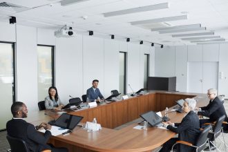 Grupo multicultural de profissionais reunido à volta de uma mesa numa sala de conferências moderna.